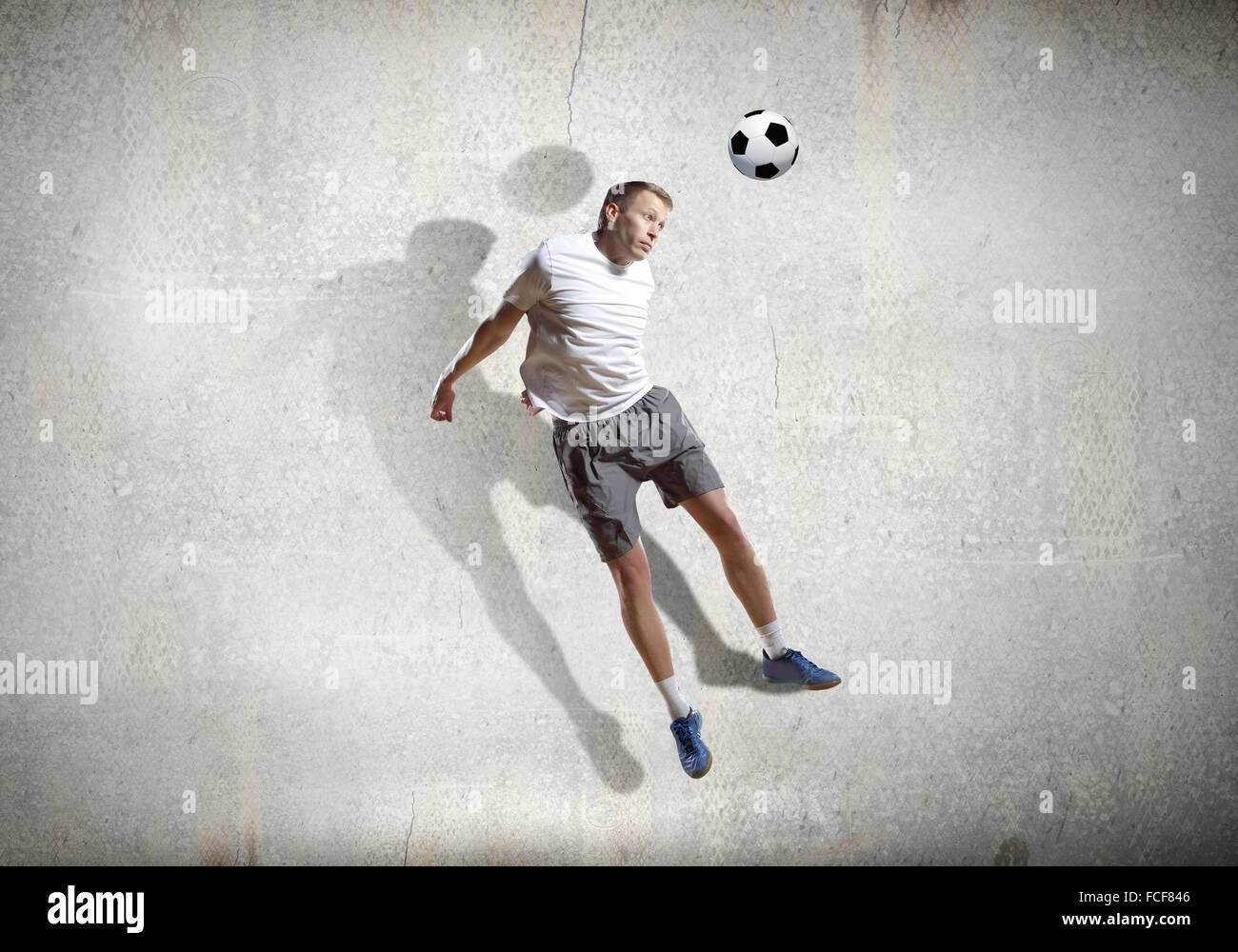 Football player kicking ball against cement background Stock Photo Alamy
