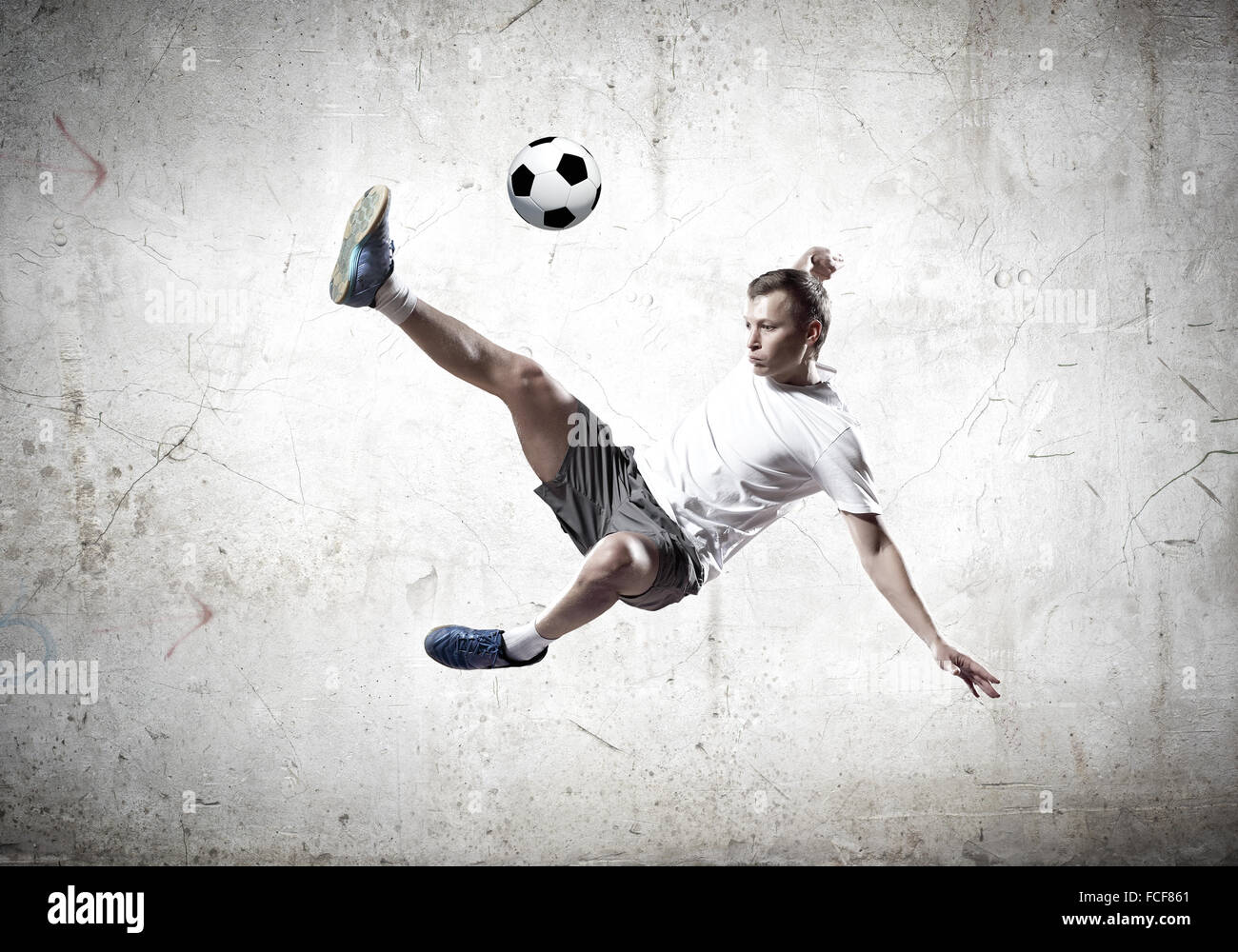 Football player kicking ball against cement background Stock Photo Alamy