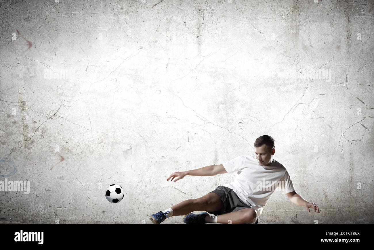 Football player kicking ball against cement background Stock Photo Alamy