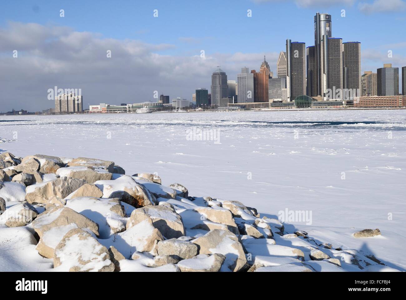 Rocky shoreline near the iced covered Detroit River with Detroit in the