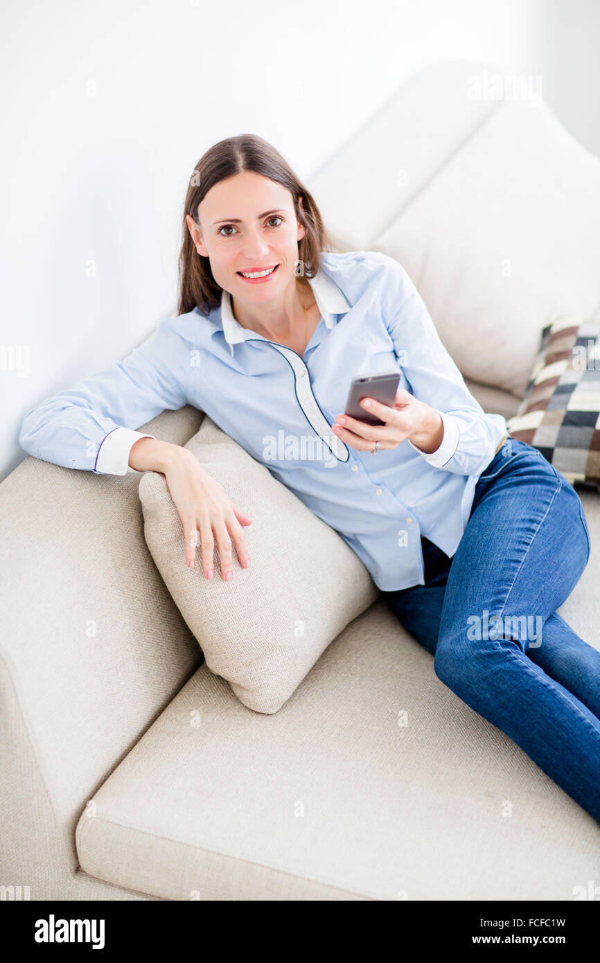 Female Using Iphone Woman looking at iphone sofa hi-res stock photography and images - Alamy