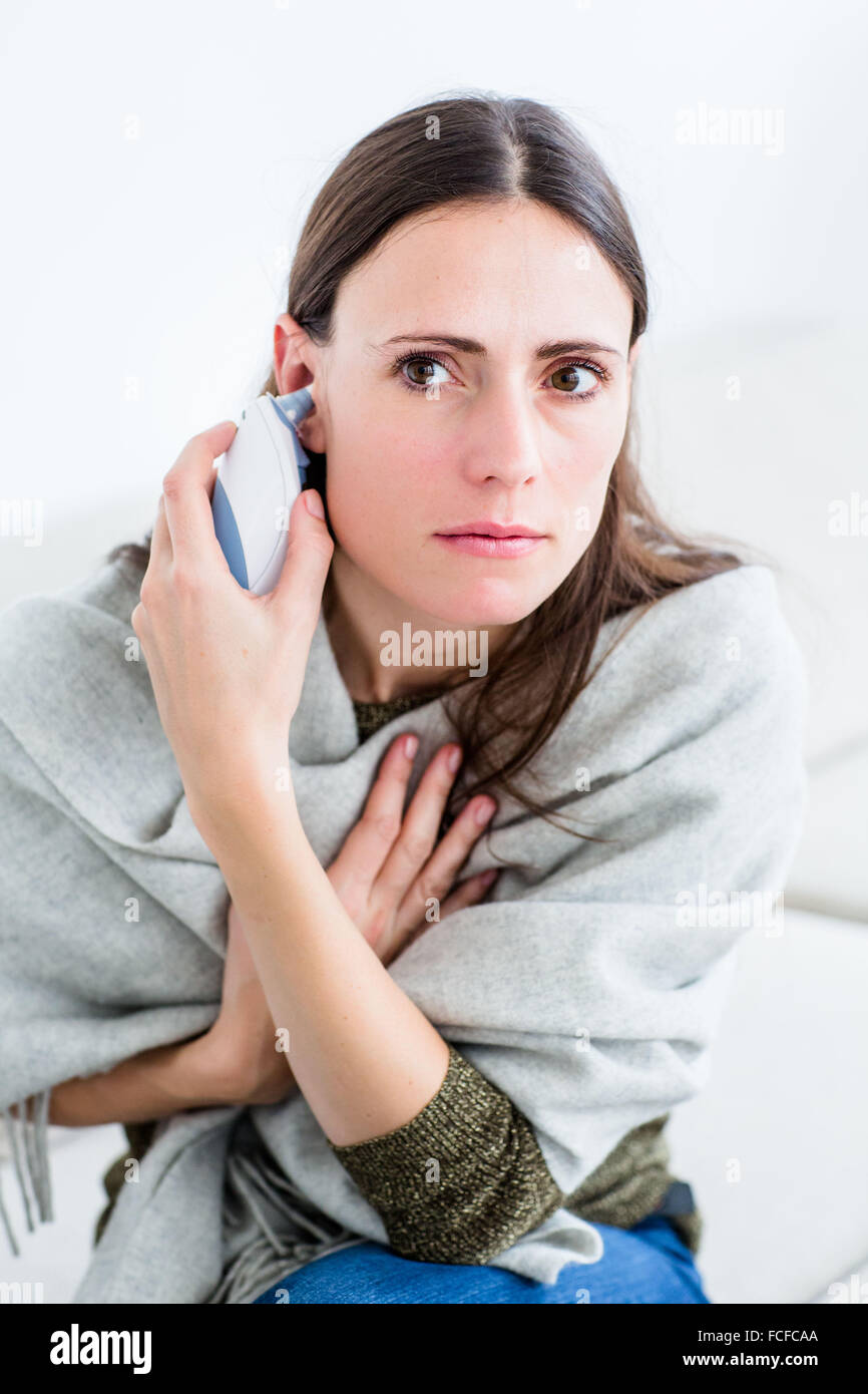 Woman taking her temperature with a digital tympanic thermometer. Stock Photo