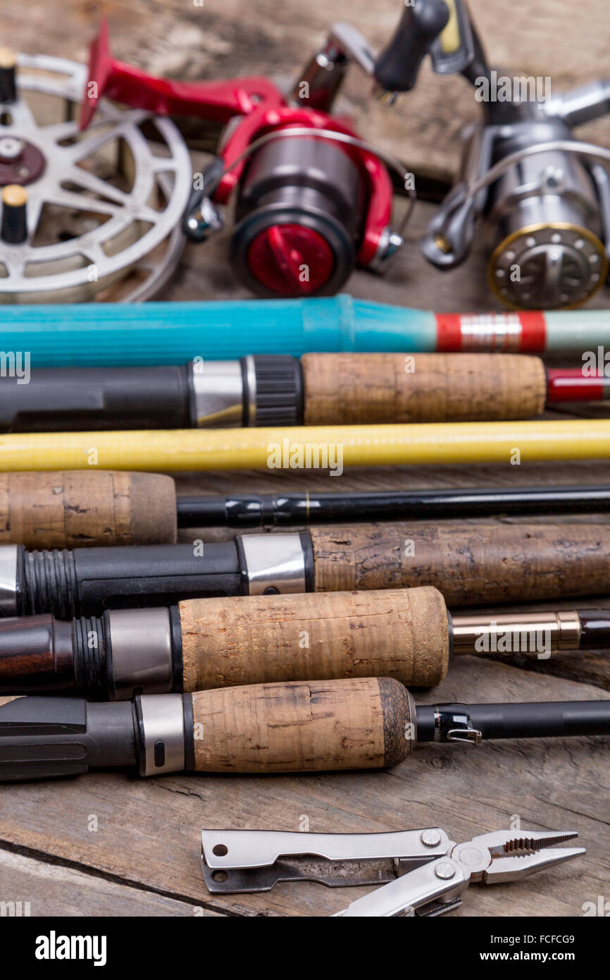 different fishing rods and reels on wooden boards background. creative idea  for design tackle service, repair Stock Photo - Alamy