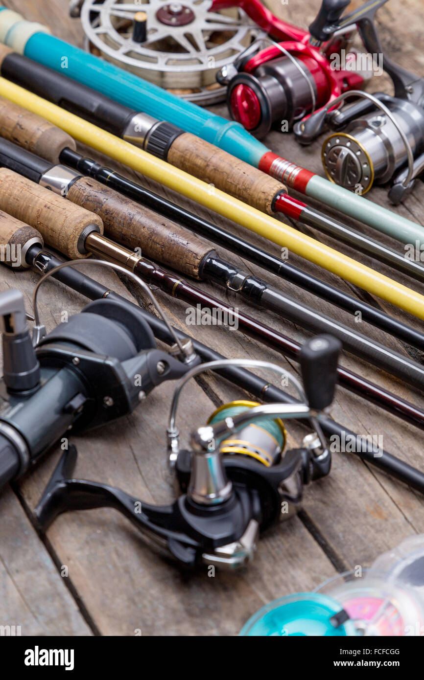 different fishing rods and reels on wooden boards background