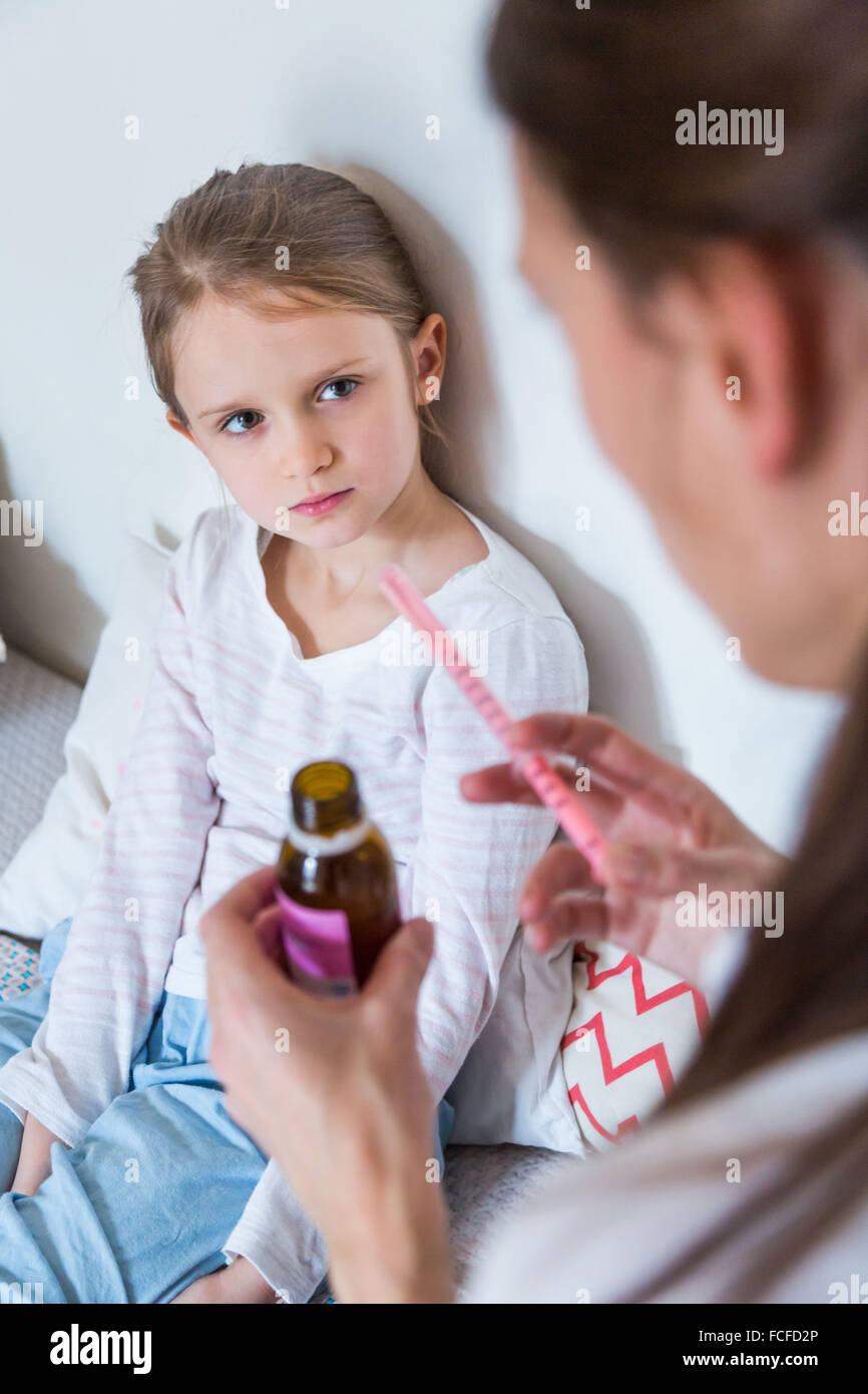 Mother giving her 6 year-old daughter syrup with a pipette. Stock Photo