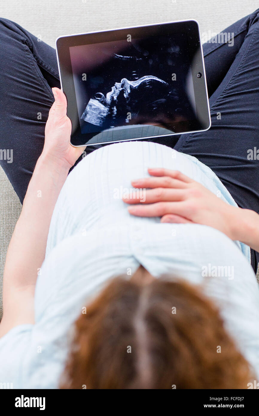 Woman looking at baby scan on a digital tablet. Stock Photo