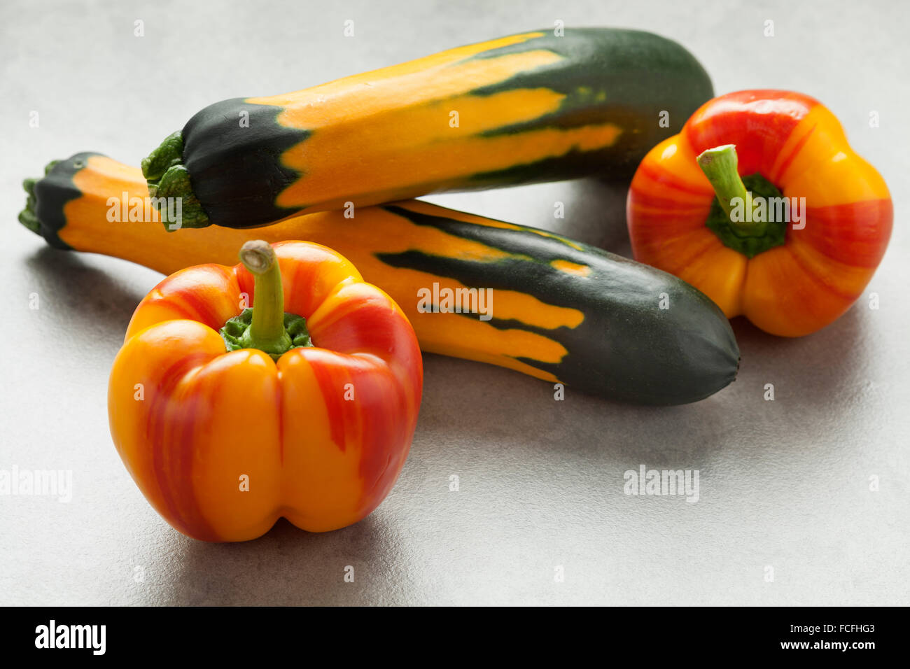 Fresh raw striped yellow and red peppers and green yellow striped zucchini Stock Photo