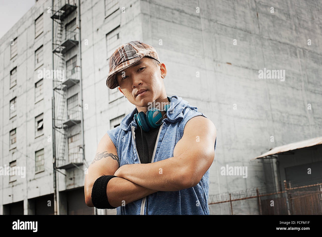 A young person in a denim sleeveless shirt, arms folded looking at the camera. Stock Photo