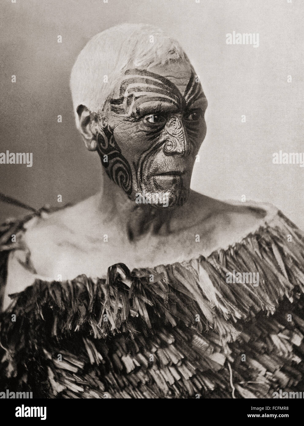 A Maori Chief from New Zealand.  The tattoo on his face is not quite complete, but the grooves in the skin produced by the peculiar method of Maori tattooing are very distinct.  He wears a cloak of flax leaves of a type which affords very efficient protection in wet weather. After a 19th century photograph. Stock Photo