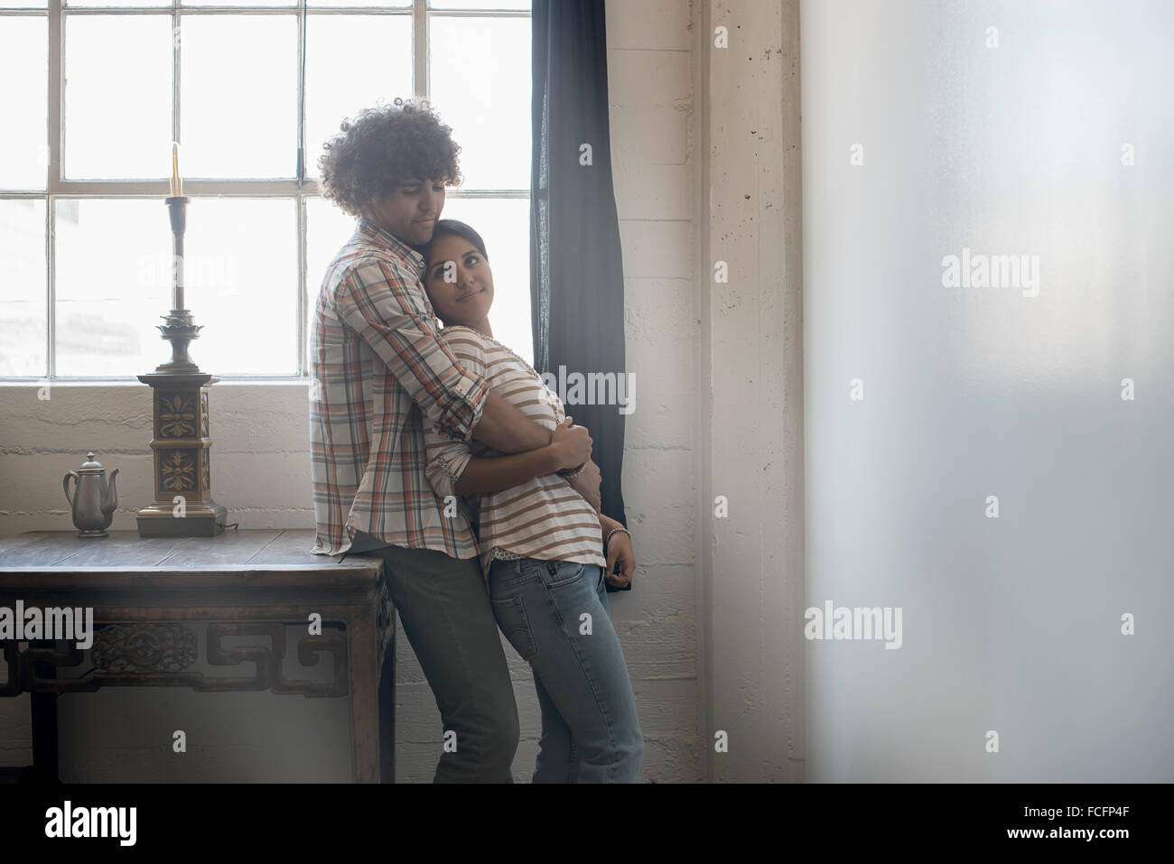 Loft living. A couple standing side by side by a window. Stock Photo