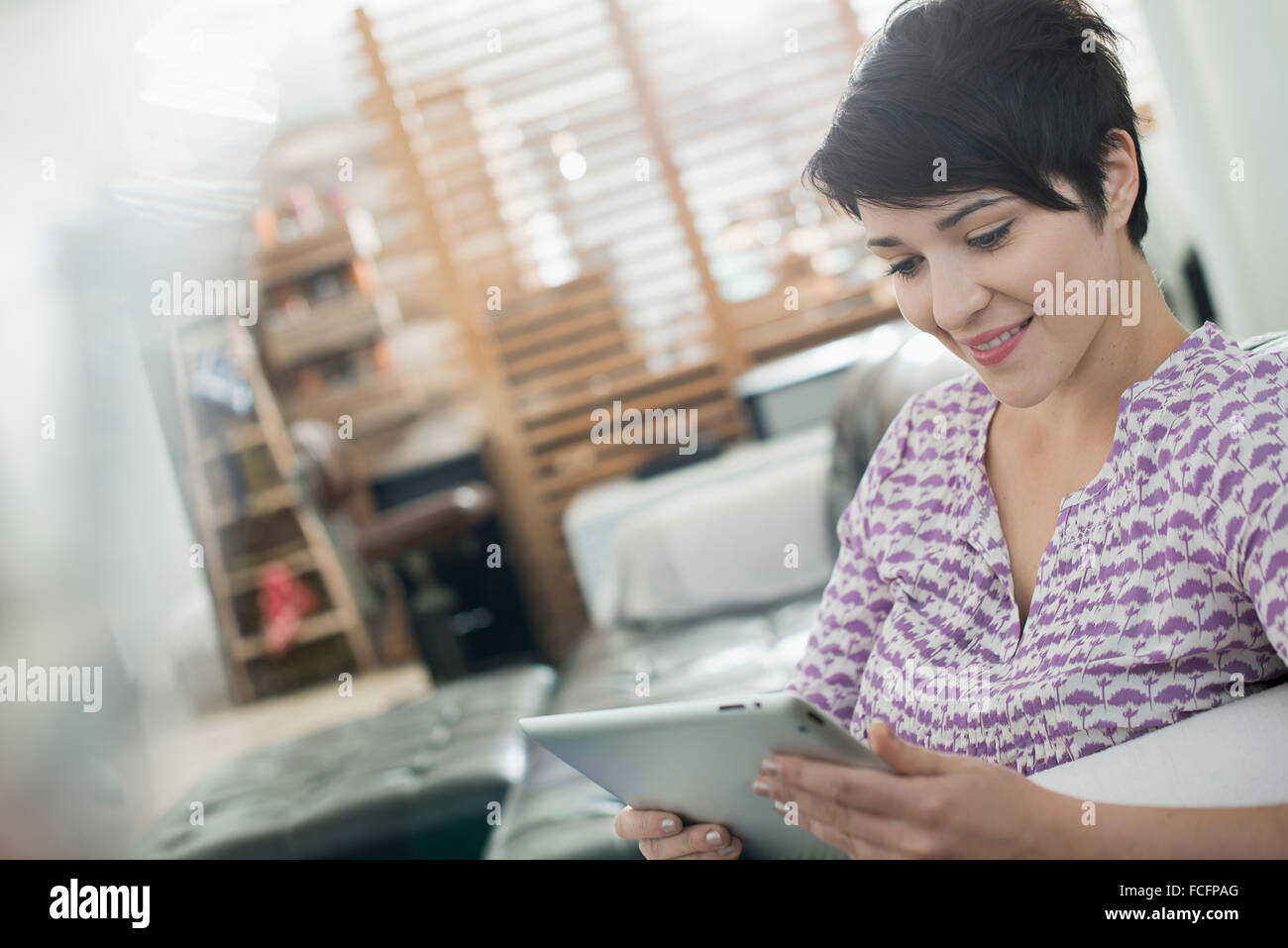 A woman sitting on a sofa using a digital tablet Stock Photo - Alamy