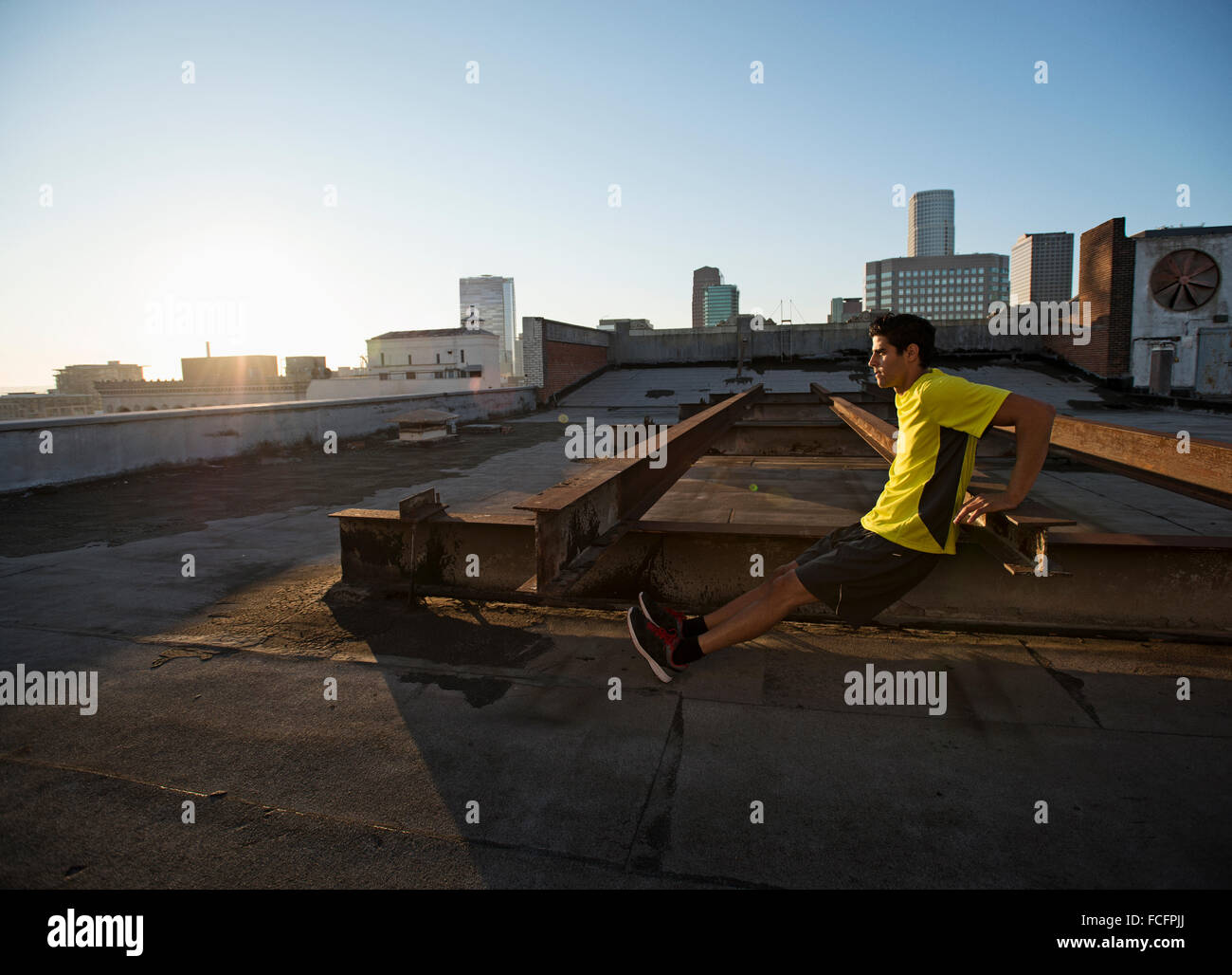 A man in exercise clothes on a rooftop overlooking the city, doing ...