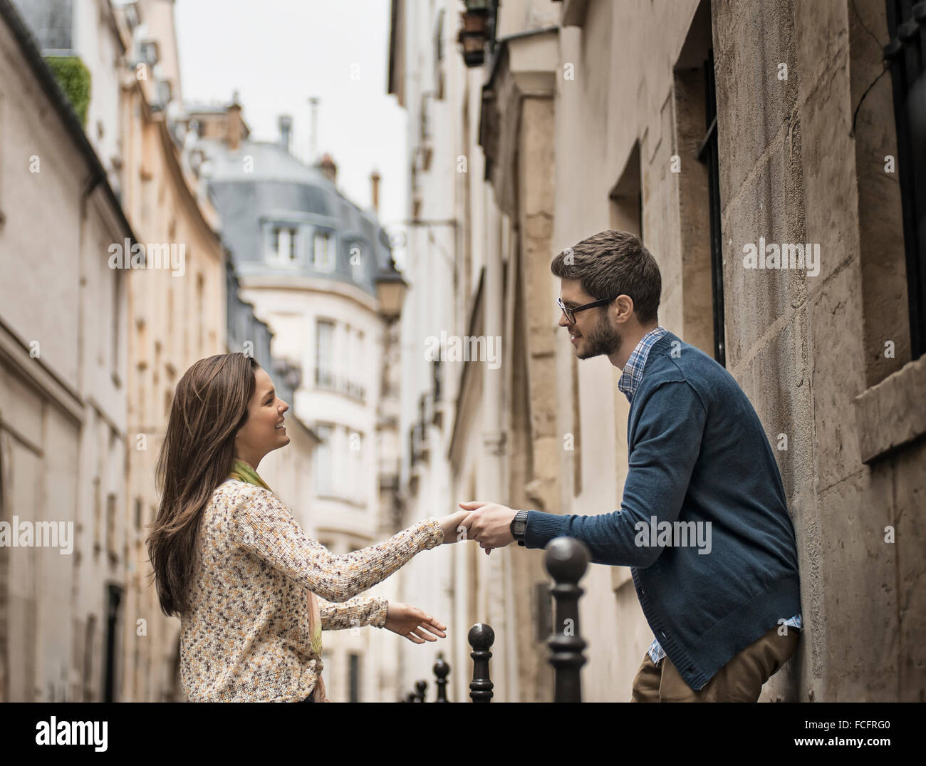 A man and woman holding hands on a city street Stock Photo - Alamy