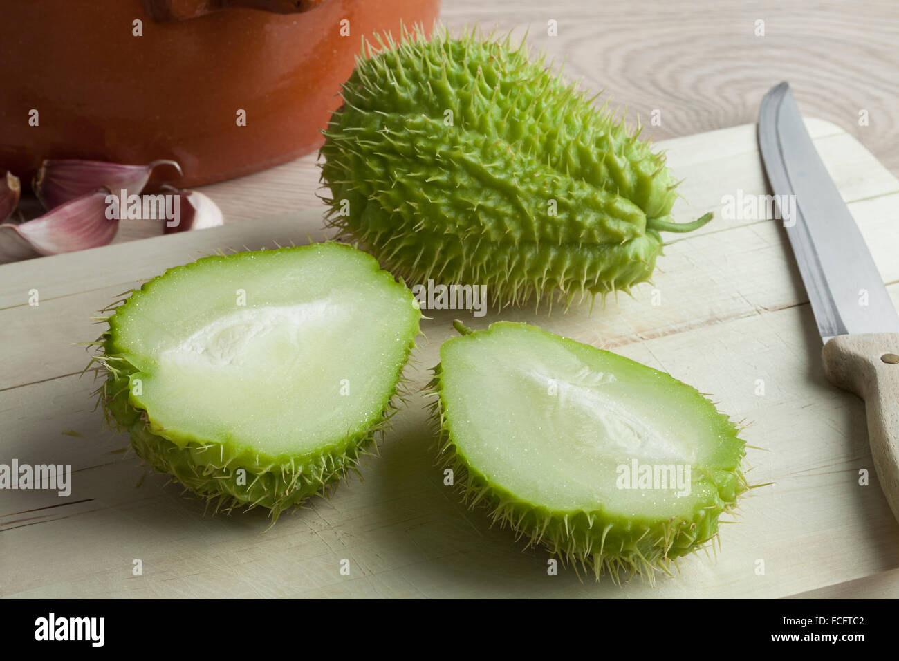 Whole and half spined fresh chayote fruit on a cutting board Stock Photo