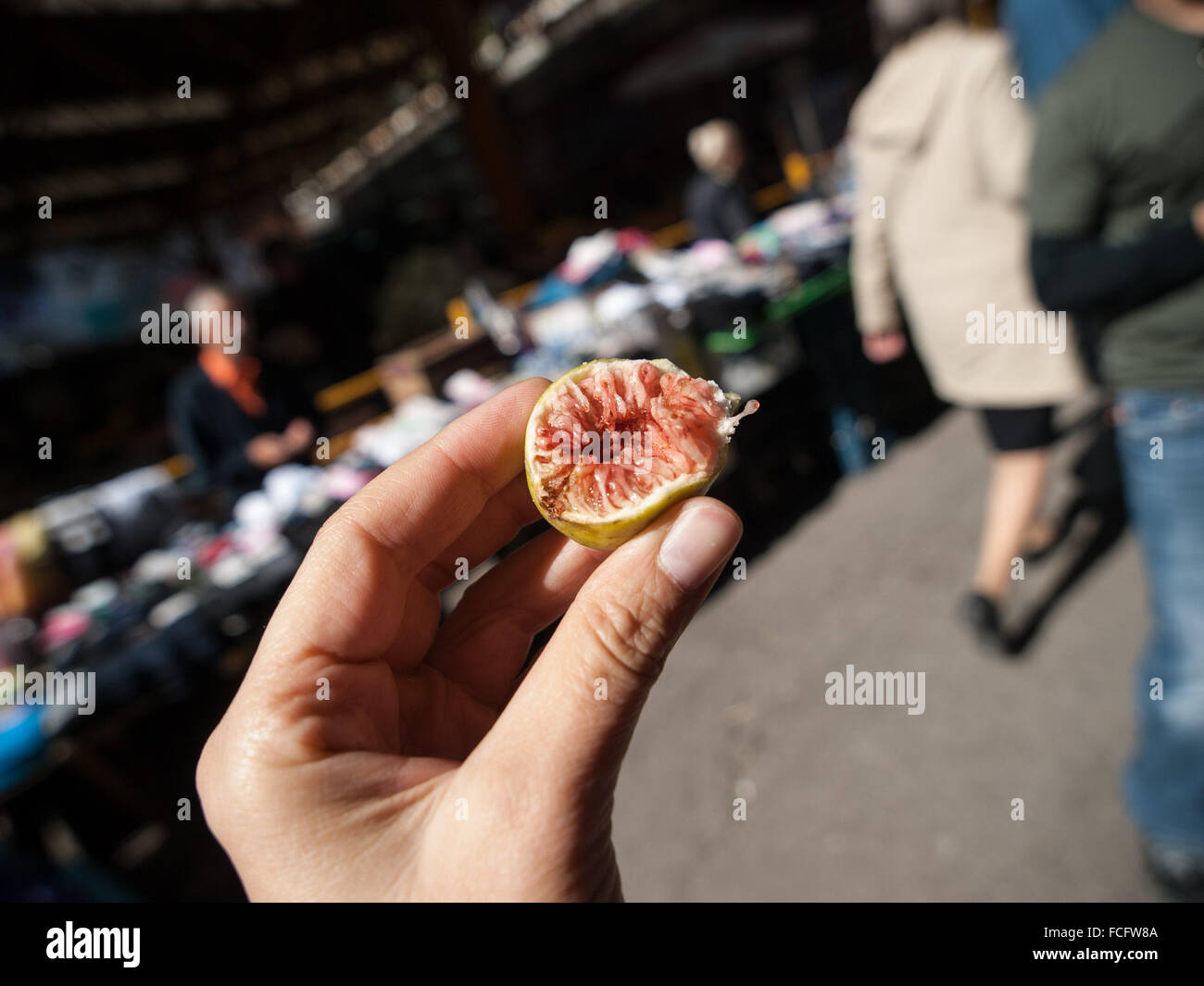 Half of a pink and green small fig in female hand at the Markale market in Sarajevo, Bosnia and Herzegovina, Europe. Stock Photo