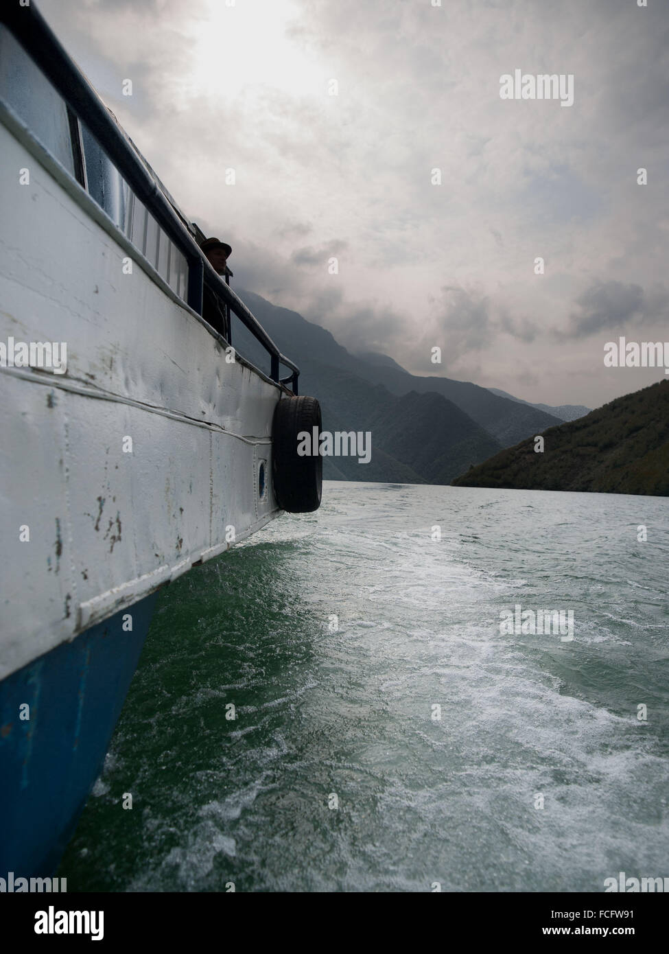 Boat ride on Lake Komani through the mountains in Albania, Europe on a cloudy rainy day. Stock Photo