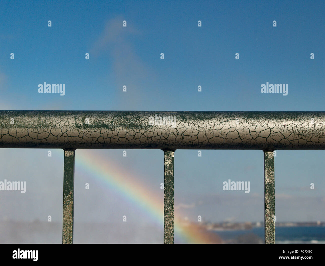 Painted green railing with crackling silver overlay in front of rainbow ...