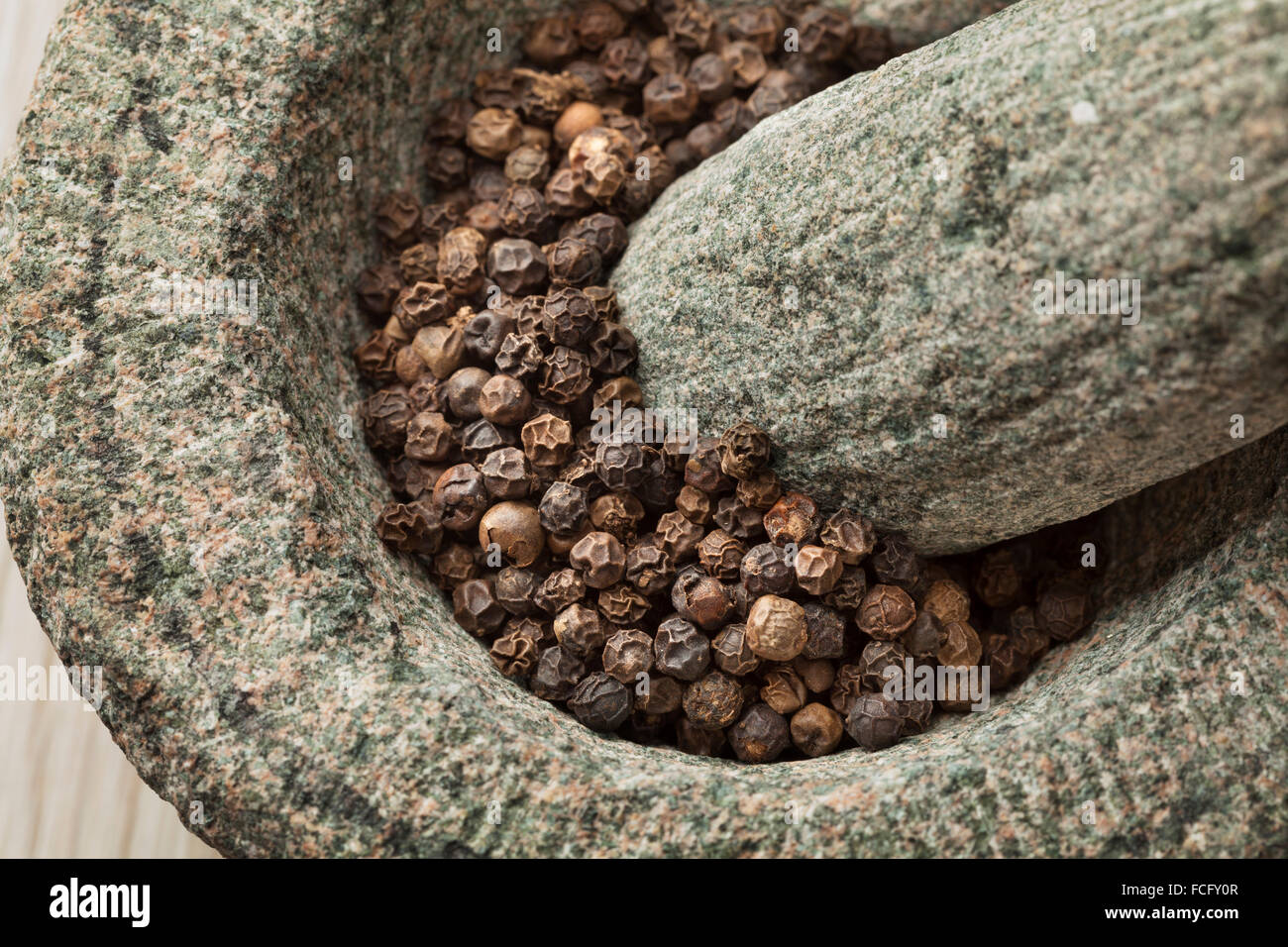 Traditional mortar and pestle with dried black pepper close up Stock Photo
