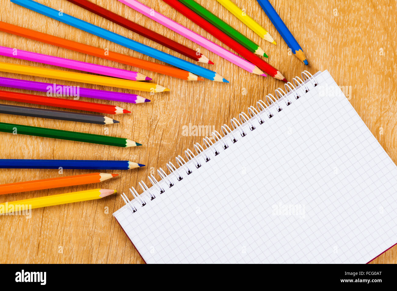 Colored pencils and notepad on wooden table Stock Photo - Alamy image.