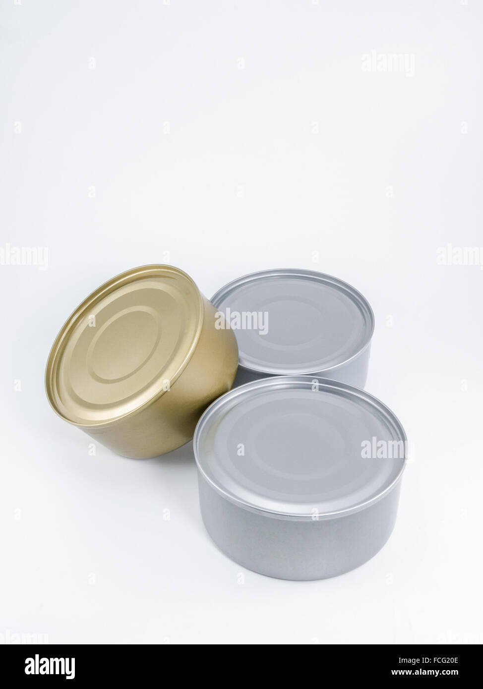 Two silver and one gold can of tuna with no label agaisnt a white background. Stock Photo
