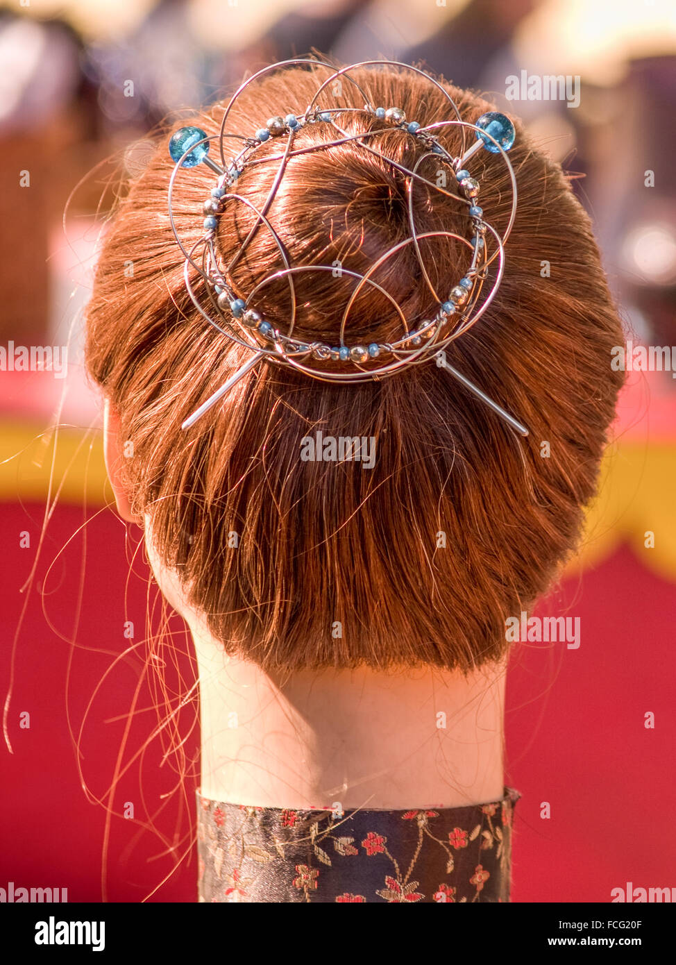 Neck and back of head of mannequin with red hair in a bun being held up by wire hair pins at Renaissance Festival in Michigan. Stock Photo
