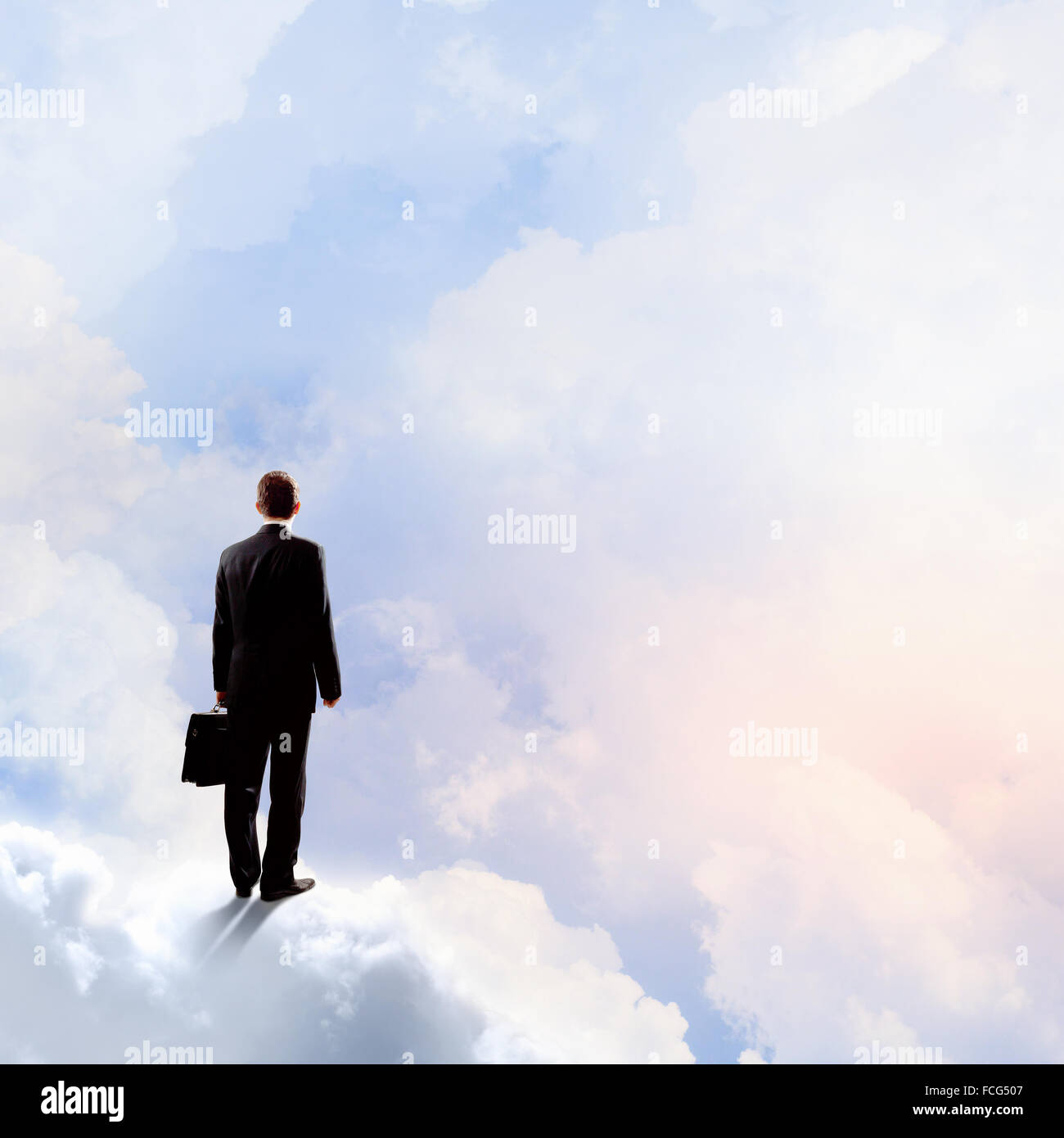 Back view of businessman standing on cloud high in sky Stock Photo - Alamy