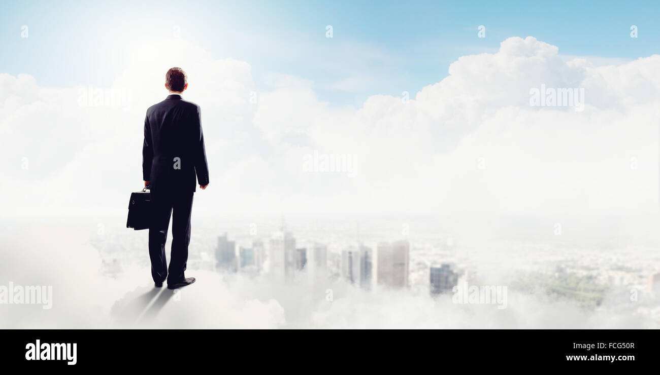 Back view of businessman standing on cloud high in sky Stock Photo - Alamy
