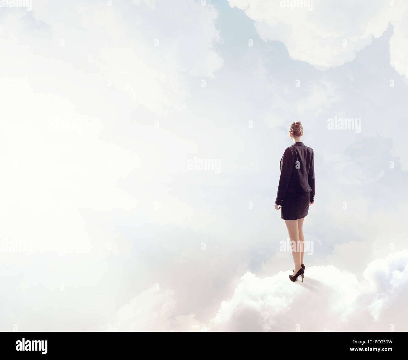 Back view of businesswoman standing on cloud high in sky Stock Photo ...