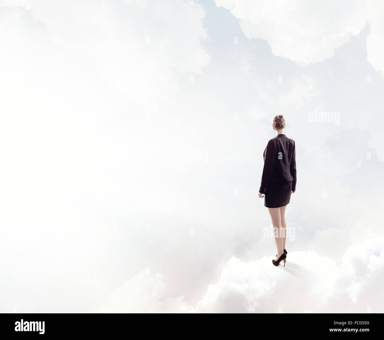 Back view of businesswoman standing on cloud high in sky Stock Photo ...