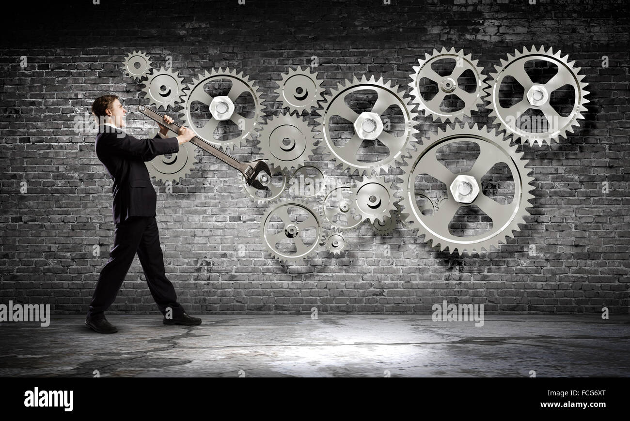 Young businessman fixing gears mechanism with wrench Stock Photo Alamy