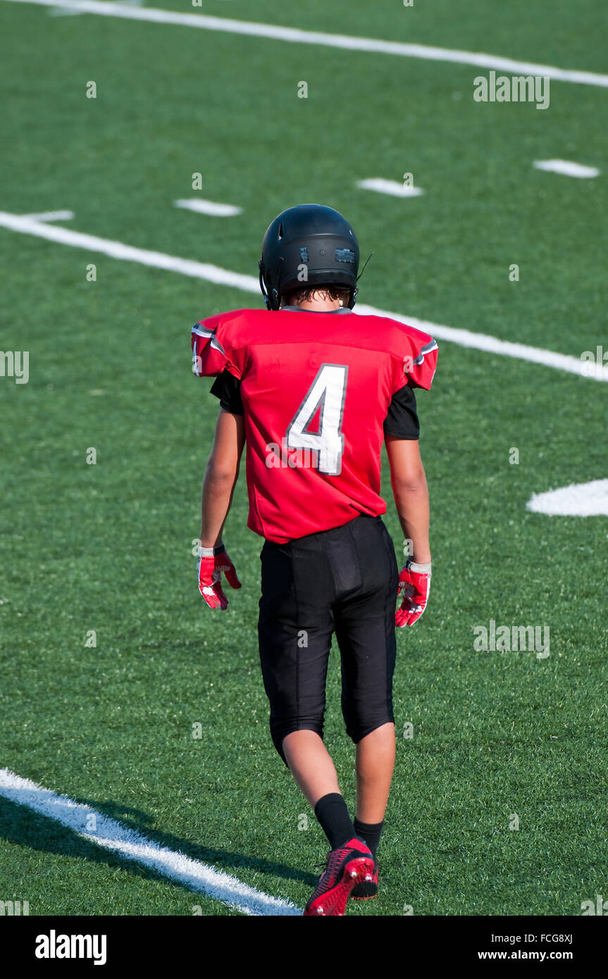 American football teenager on the field looking down. Stock Photo