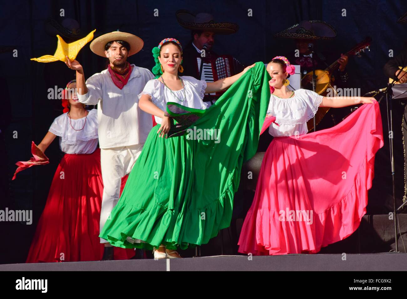 Men and women are dancing a folk dance of Mexico. The dancers wear