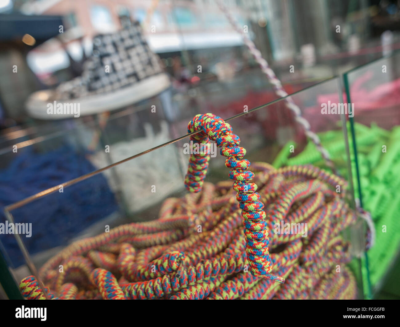 Clear boxes of curly colourful shoelaces for sale at a store Stock