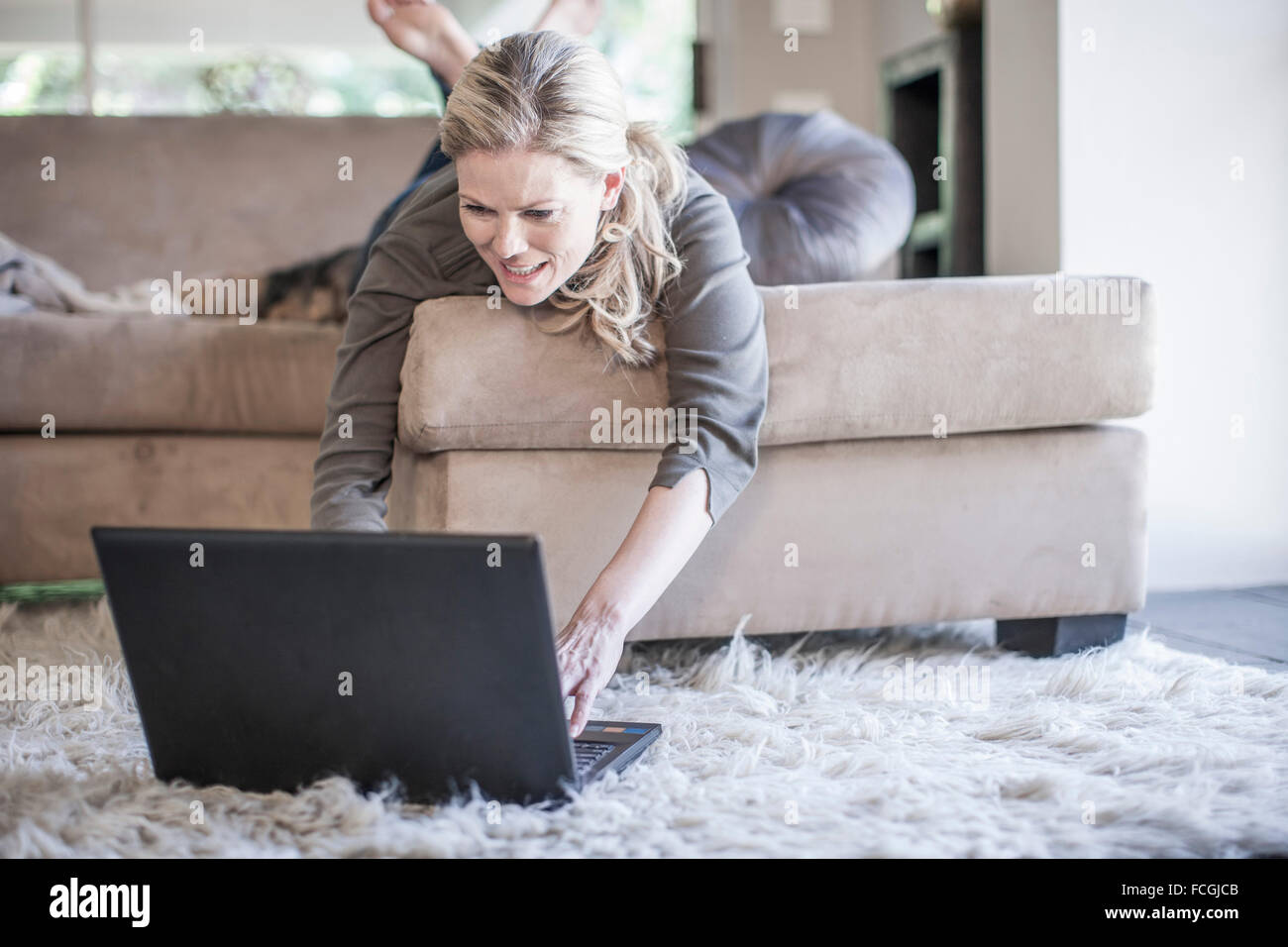 Woman lying on couch using laptop Stock Photo - Alamy
