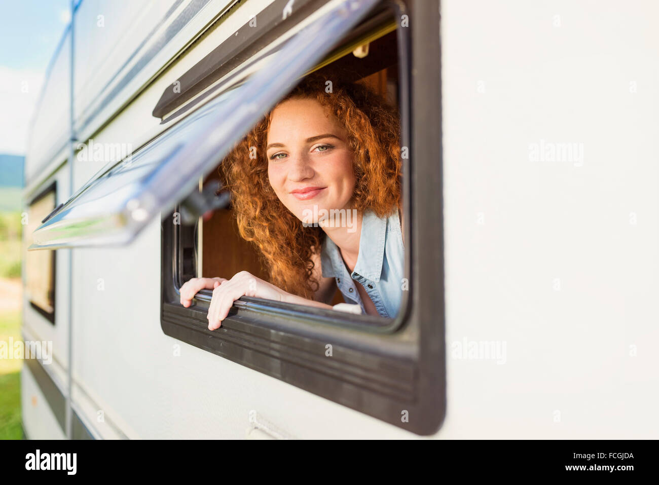 Portrit of smiling young woman  looking through window of caravan Stock Photo