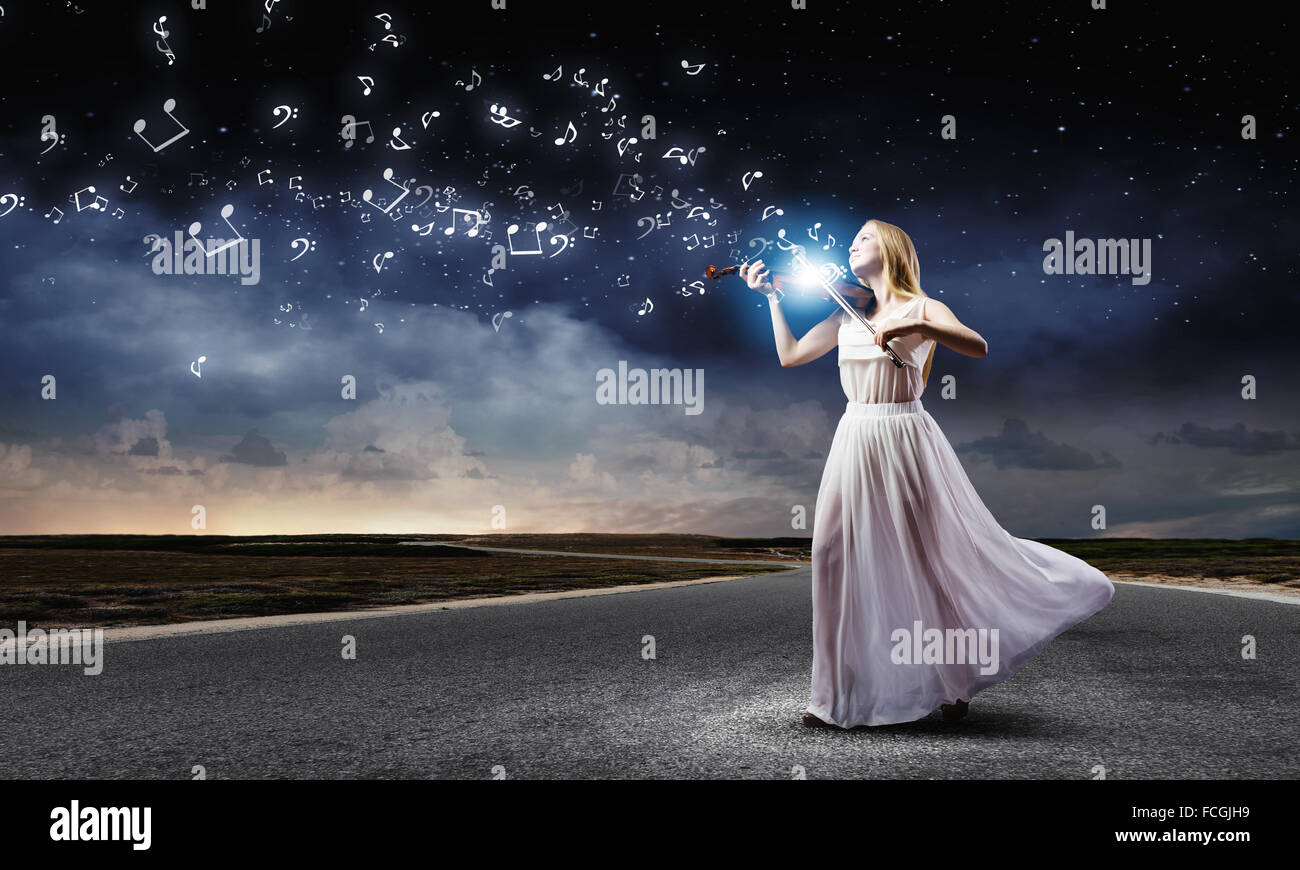 Young woman in white dress playing violin at night Stock Photo - Alamy