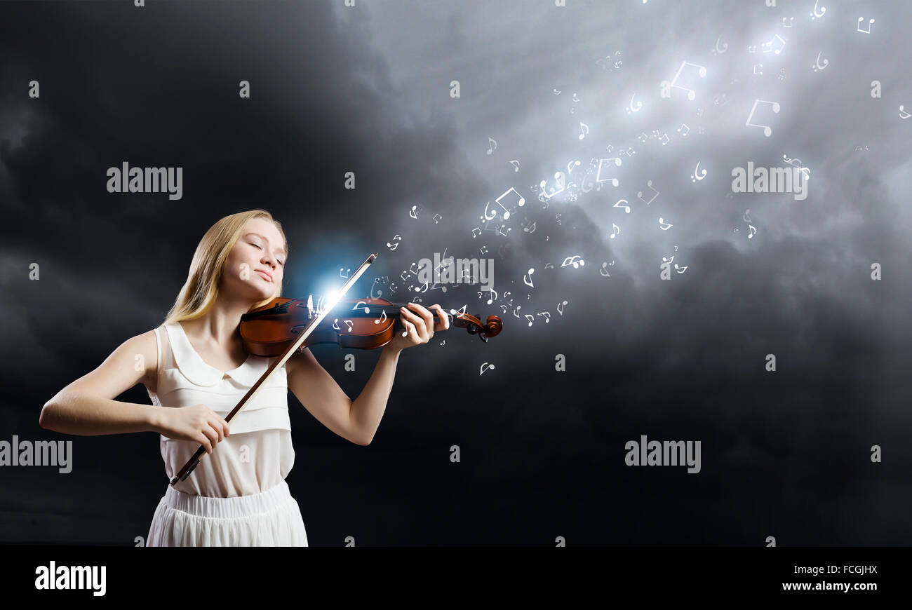 Young woman in white dress playing violin at night Stock Photo - Alamy