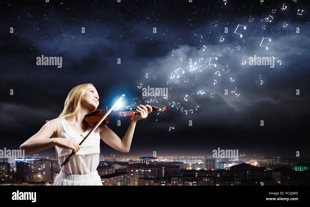 Young woman in white dress playing violin at night Stock Photo - Alamy