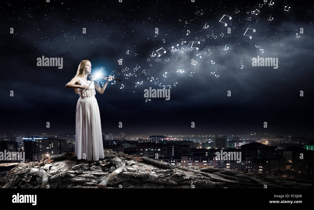 Young woman in white dress playing violin at night Stock Photo - Alamy