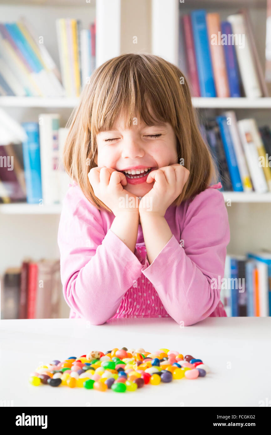 Portrait of smiling little girl closed eyes jelly beans lying on a