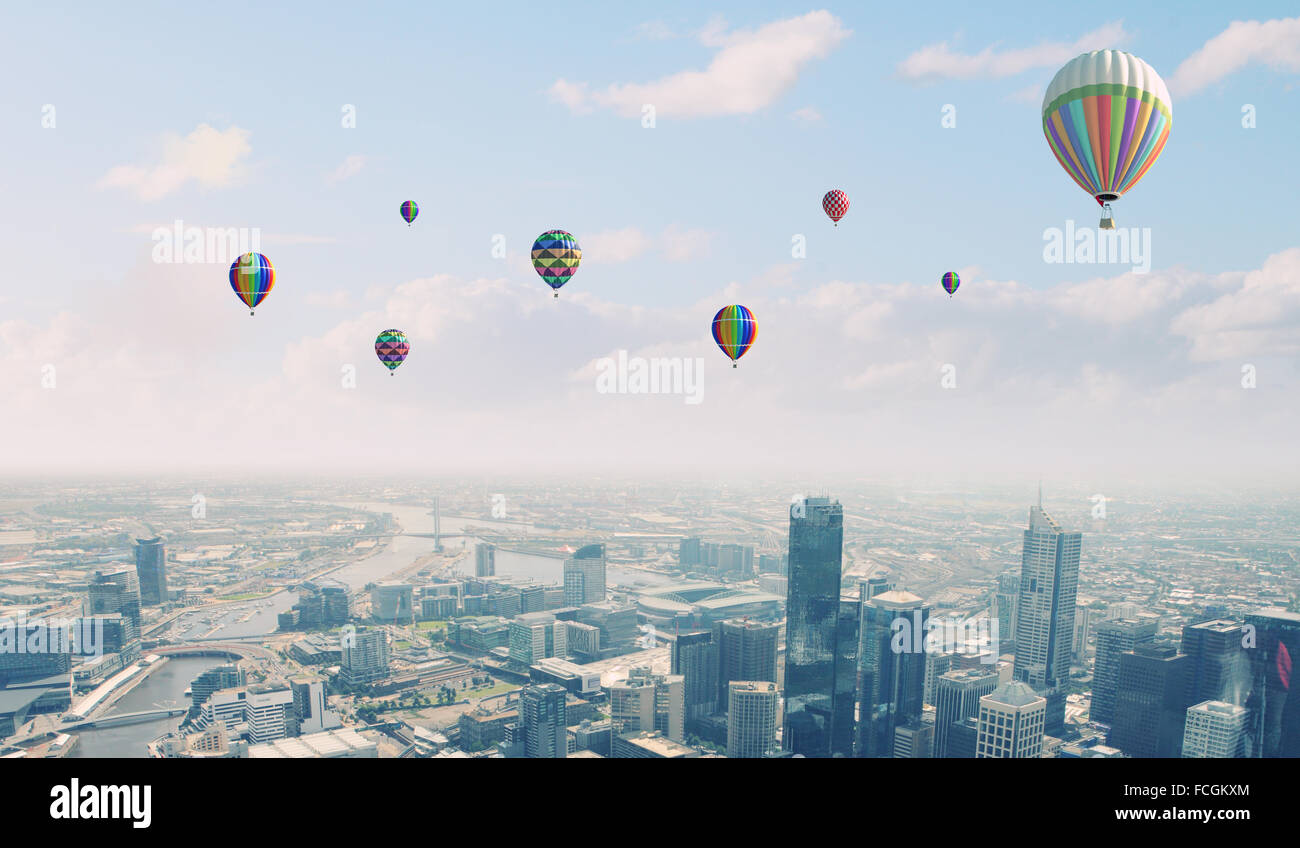 Colorful aerostats flying in clear sky above modern city Stock Photo ...