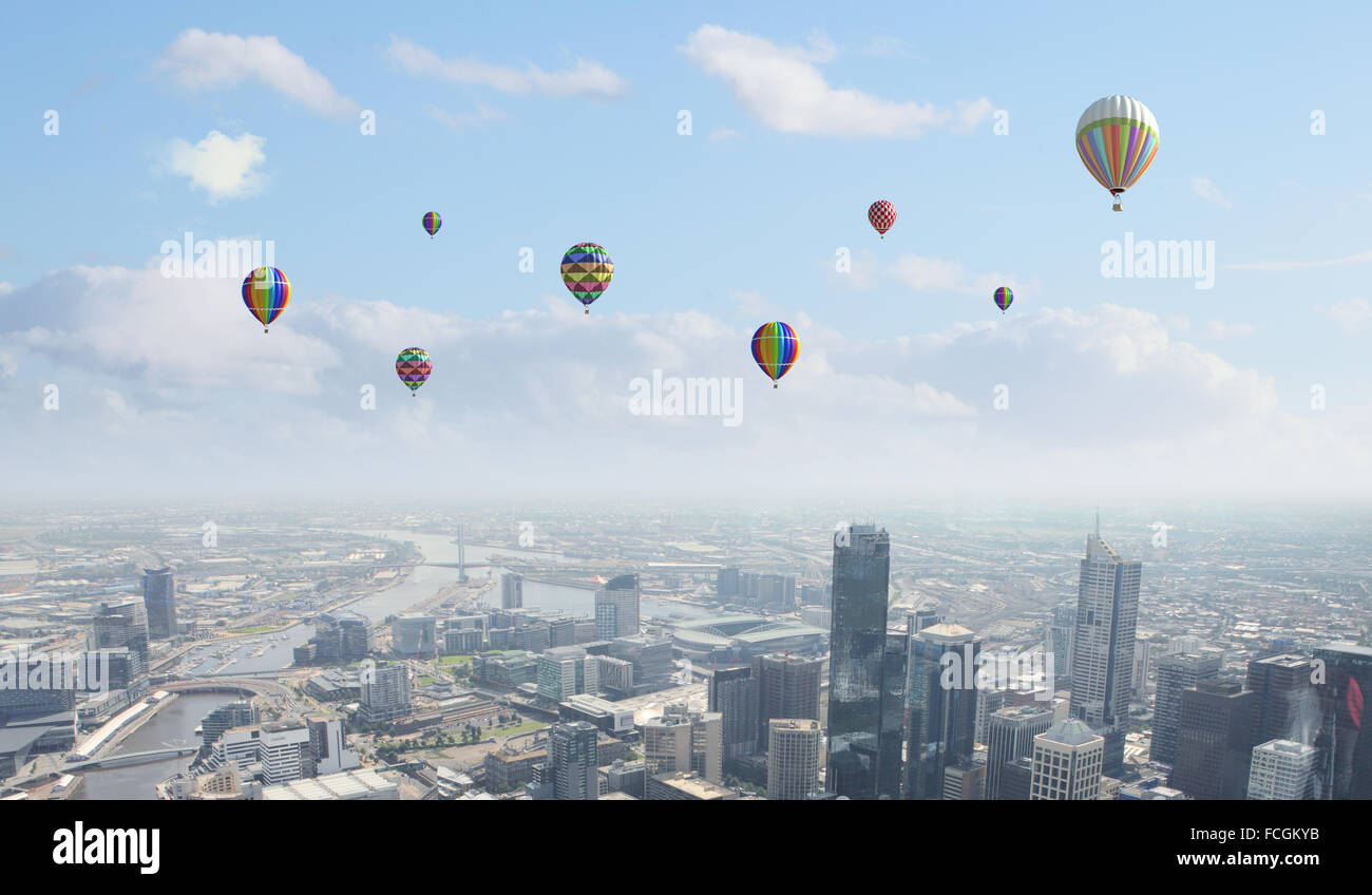 Colorful aerostats flying in clear sky above modern city Stock Photo ...