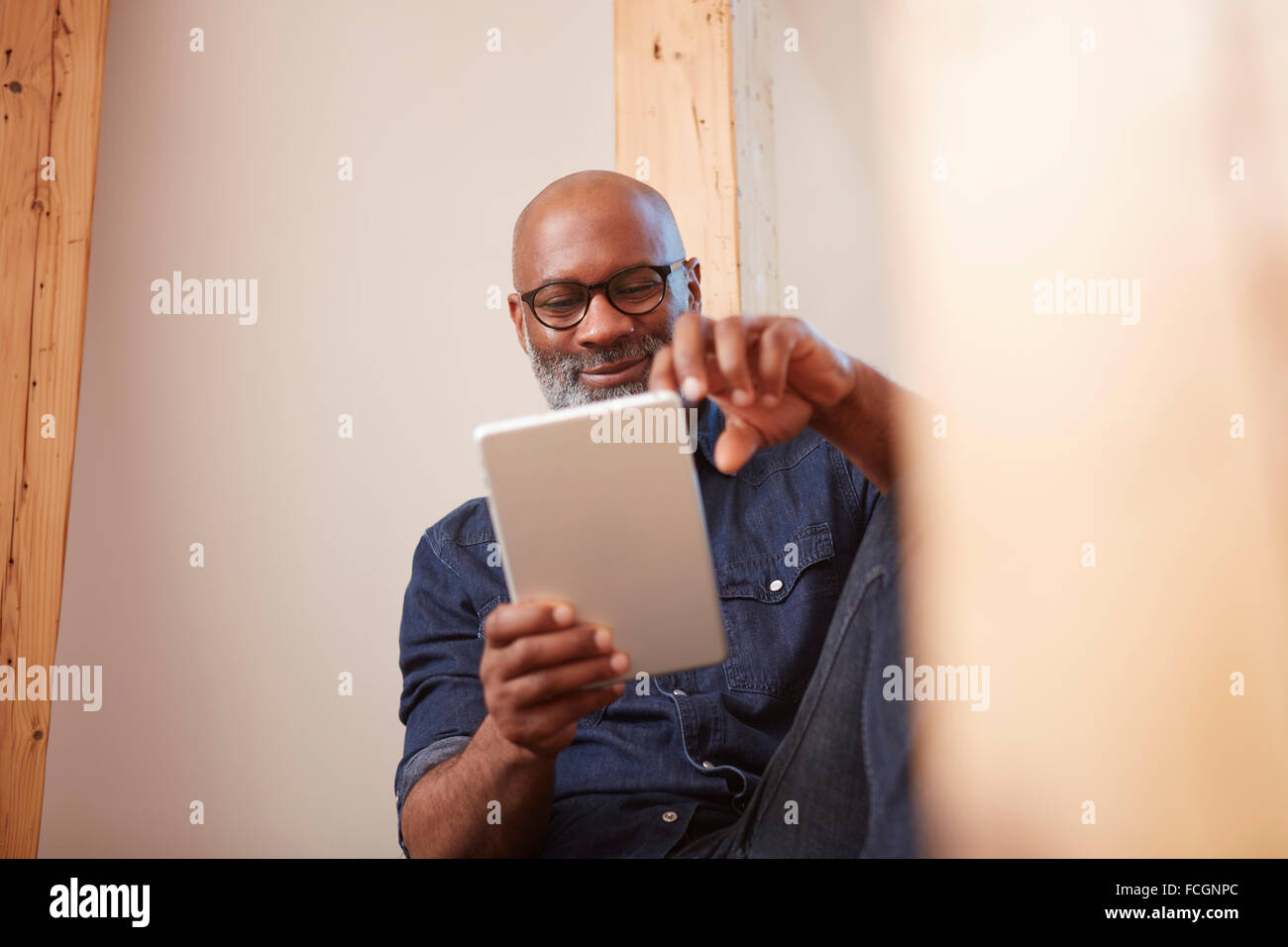 Portrait of smiling man looking at digital tablet Stock Photo