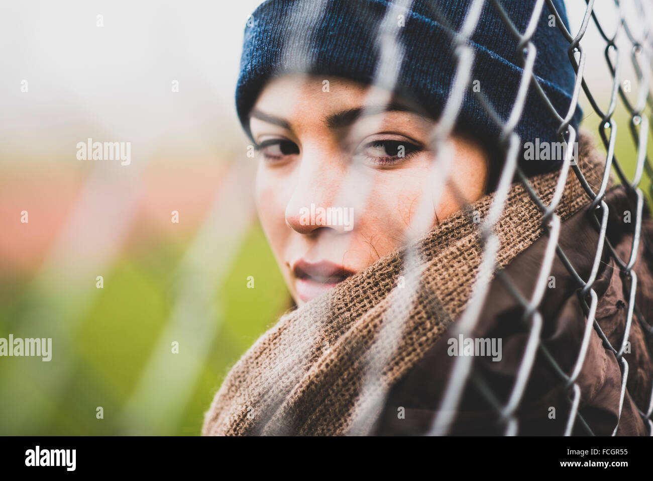 Portrait of young woman looking through wire mesh Stock Photo
