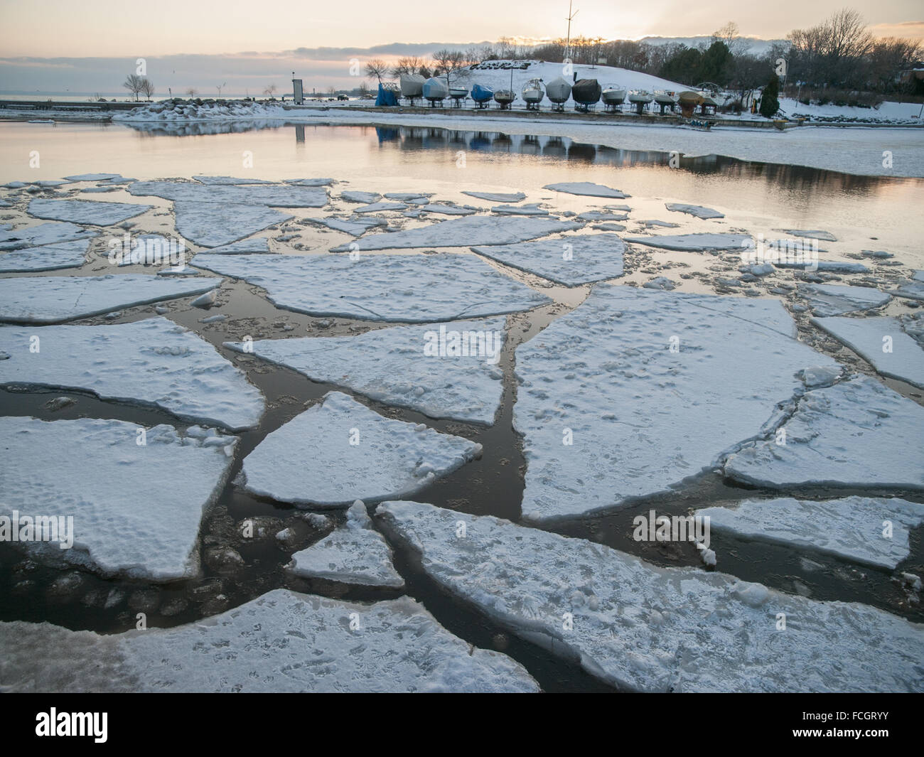 Covered boats on Lake Ontario with floating ice chunks and snow, in Oakville, Ontario, Canada in winter. Stock Photo