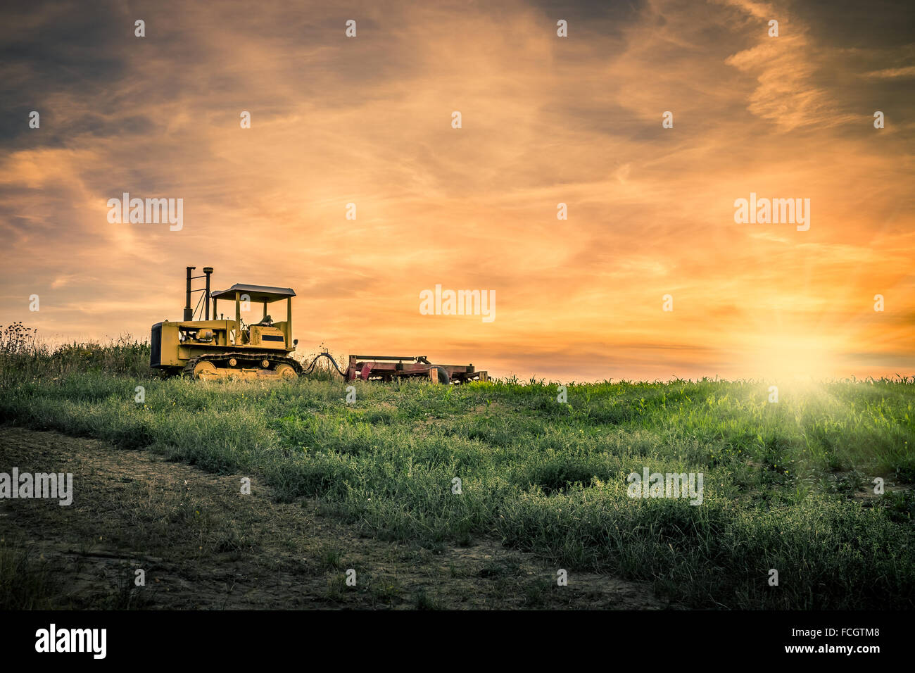 Tractor and amazing sunset with dramatic sky Stock Photo