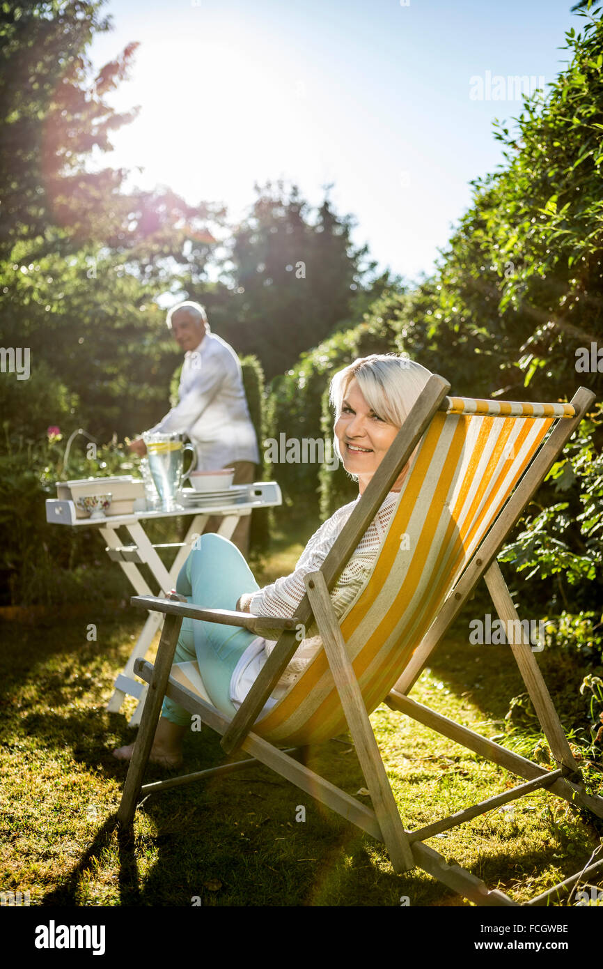 Mature woman in deckchair in garden man in background Stock Photo - Alamy