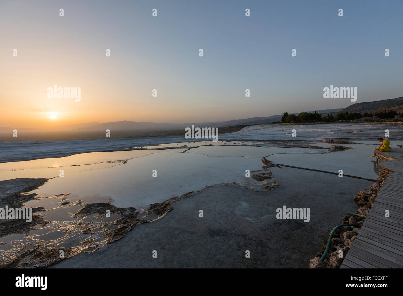 Little boy with Bugs Bunny and Tweety Bird dolls watching sunset in a pool terrace formations at Pamukkale. Stock Photo