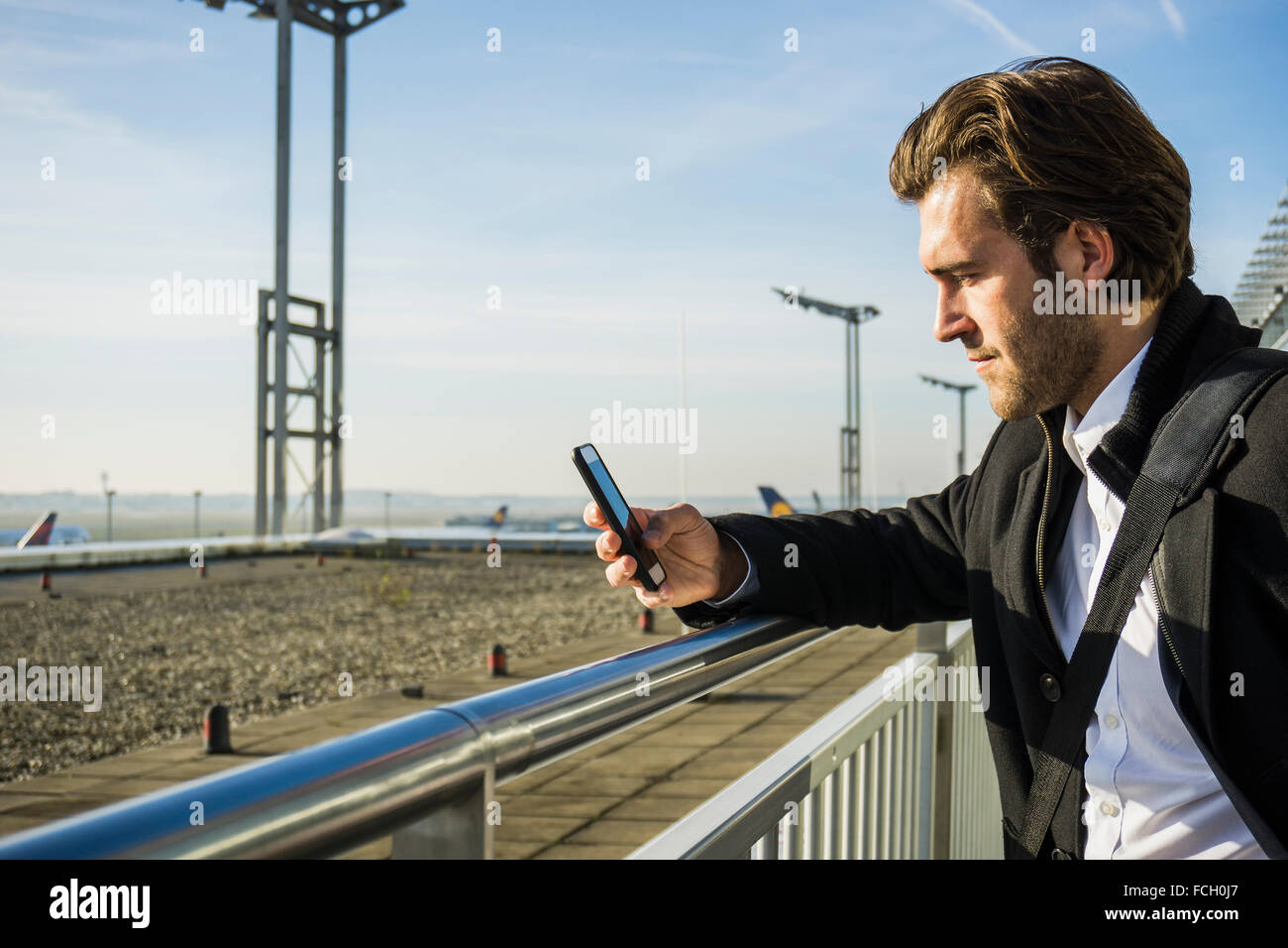 Germany Frankfurt Young businessman at the airport using smartphone Stock Photo