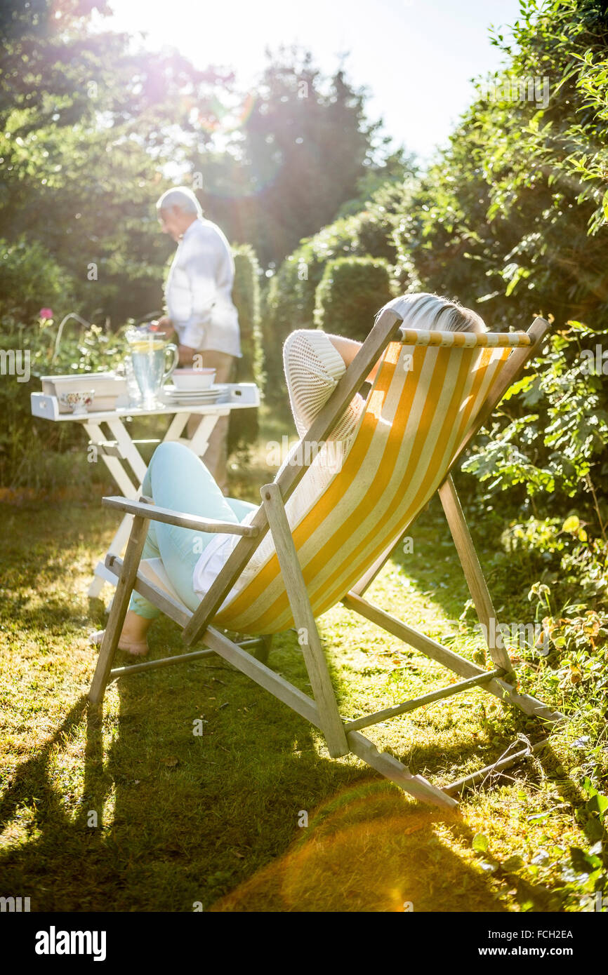 Mature woman relaxing in deckchair in garden man in background Stock ...